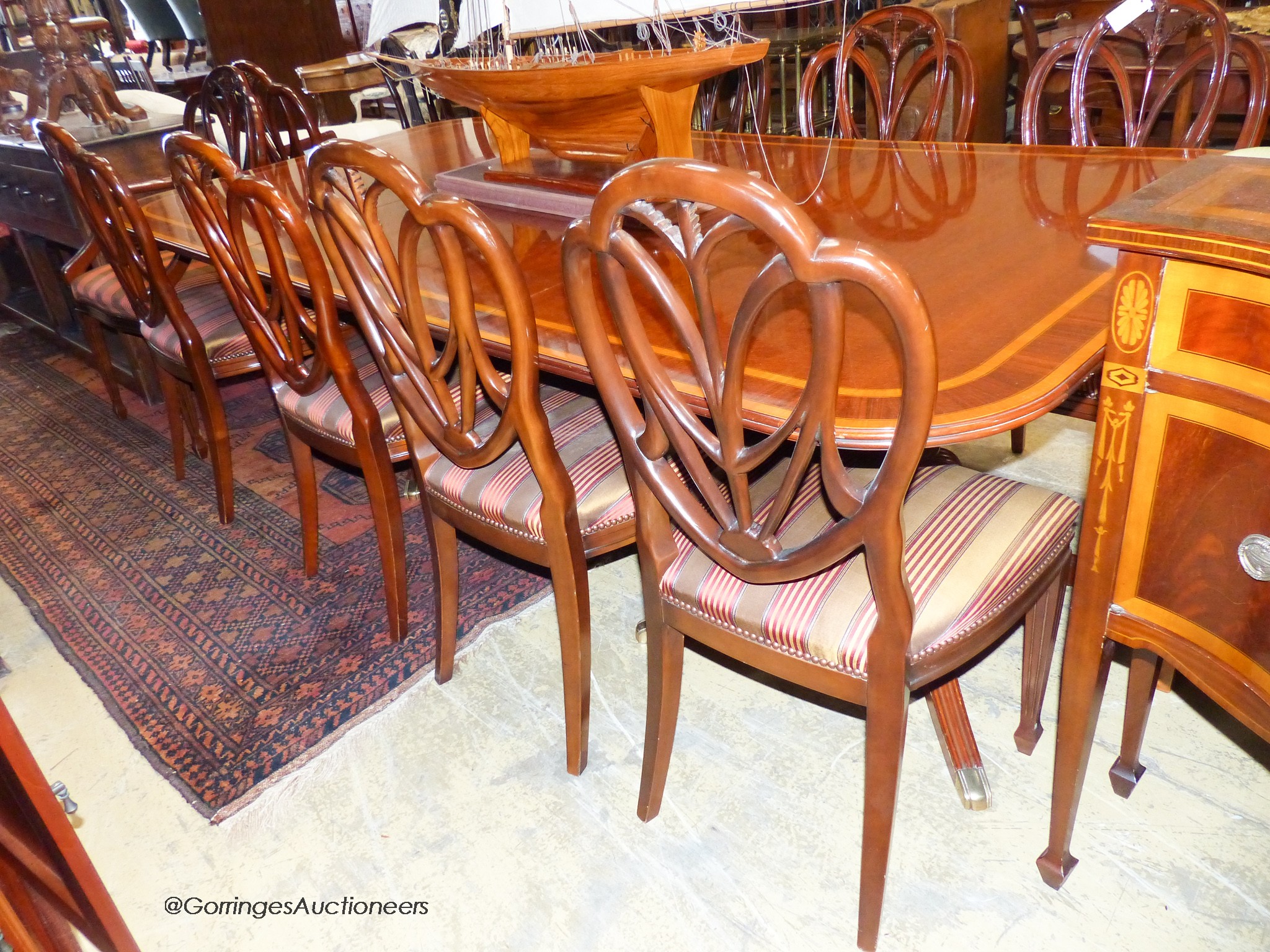 A reproduction Sheraton inlaid mahogany dining room suite, comprising twin pillar extending dining table, 240cm extended, one spare leaf, ten chairs, two with arms and sideboard. W-124, H-72cm.